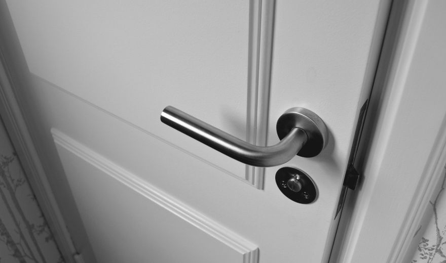 A door handle on the outside of a white door.