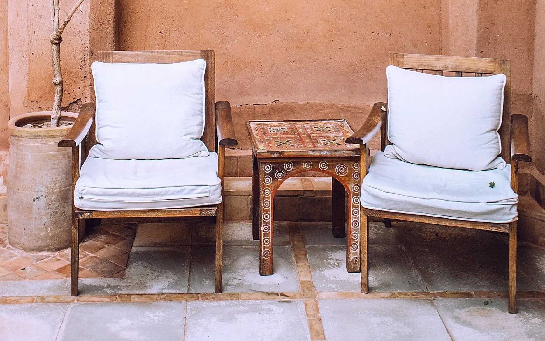 Two wooden chairs and a table in front of a wall.